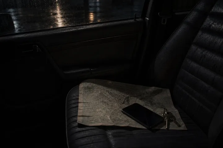 Sedile del passeggero con mappa, chiavi e telefono spento in auto di notte