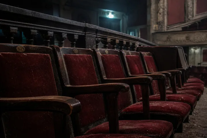 Balconata teatrale abbandonata con una sedia impossibile numerata 1613 nella penombra