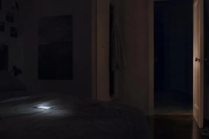 Camera vuota illuminata dal telefono dopo una seduta di possessione