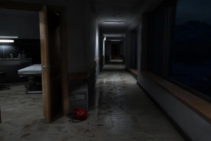 Corridoio notturno di un resort alpino con impronte umide e una porta socchiusa